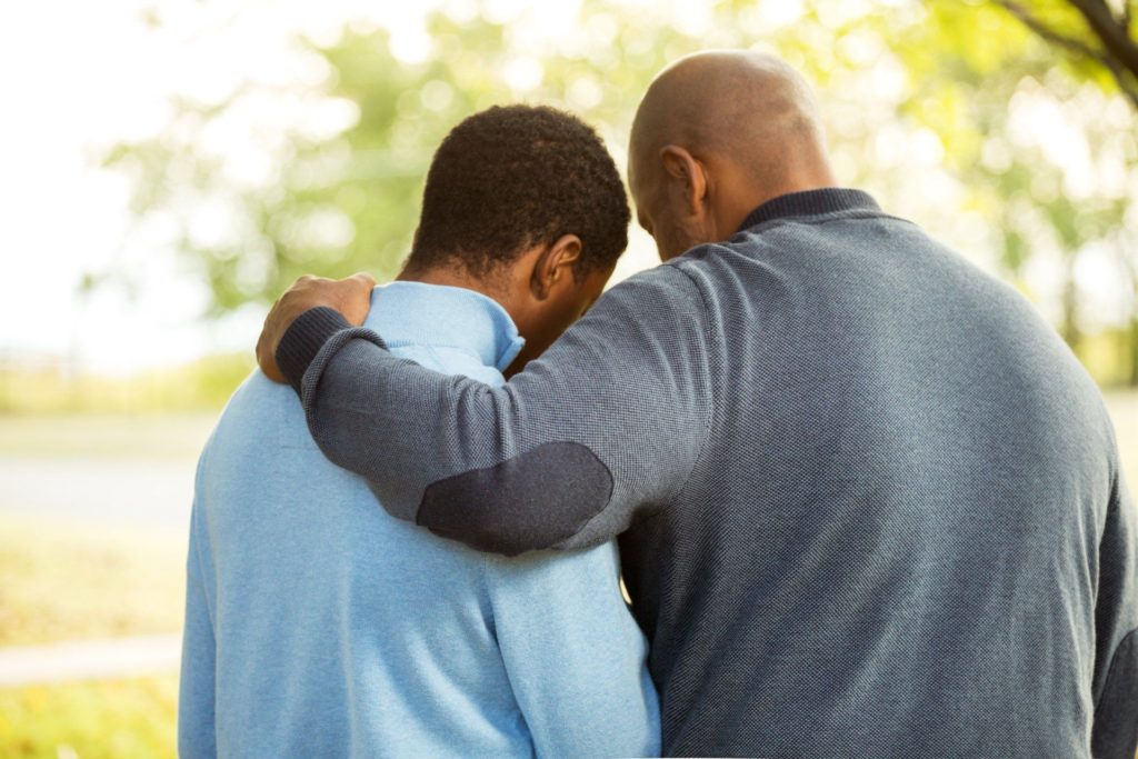 father consoling teenage son
