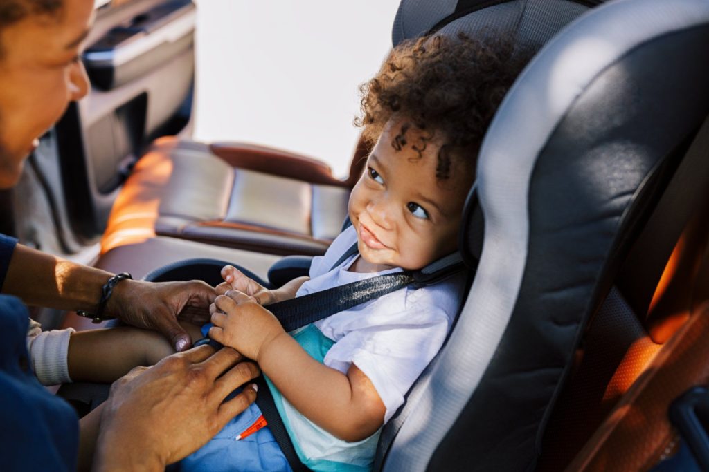 child being buckled into carseat