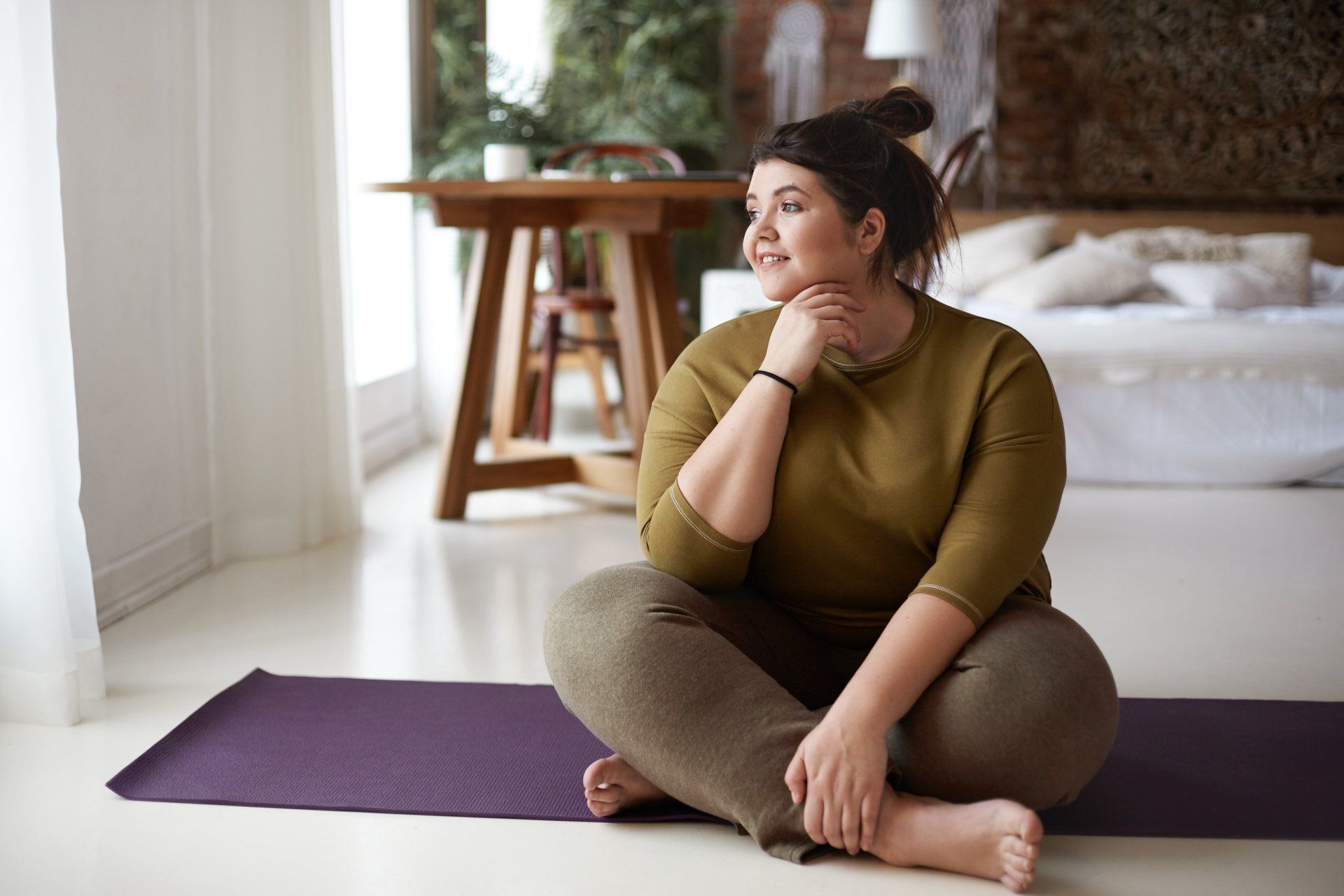 young woman sitting on yoga mat and meditating
