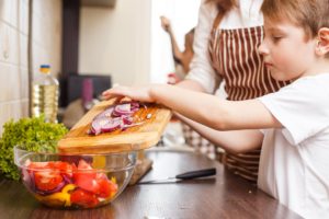 young child preparing ingredients with mother and sister