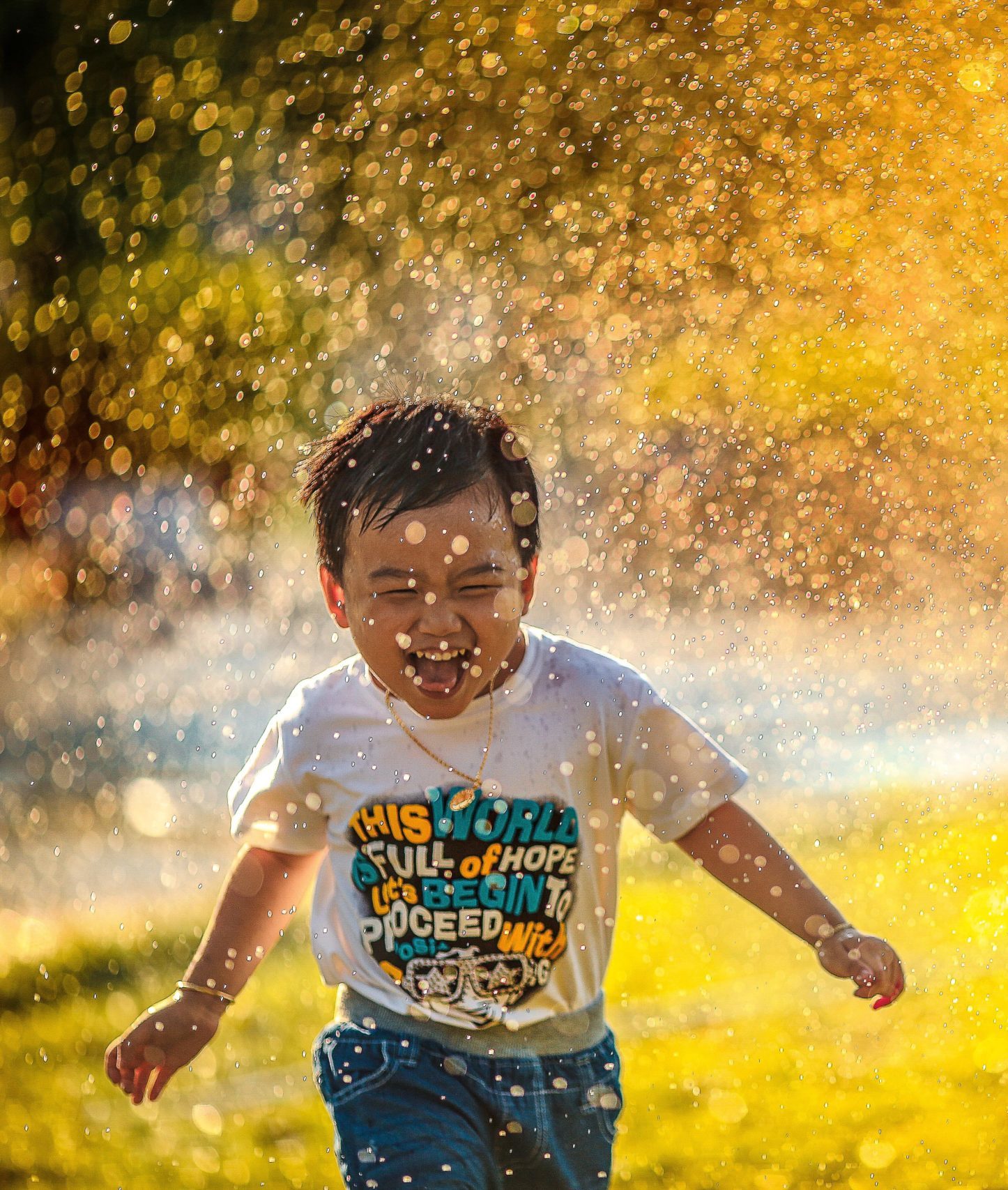 young child playing in sprinklers